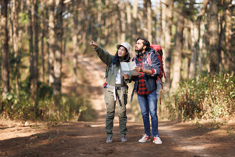 Adventurous couple looking the map in the forest