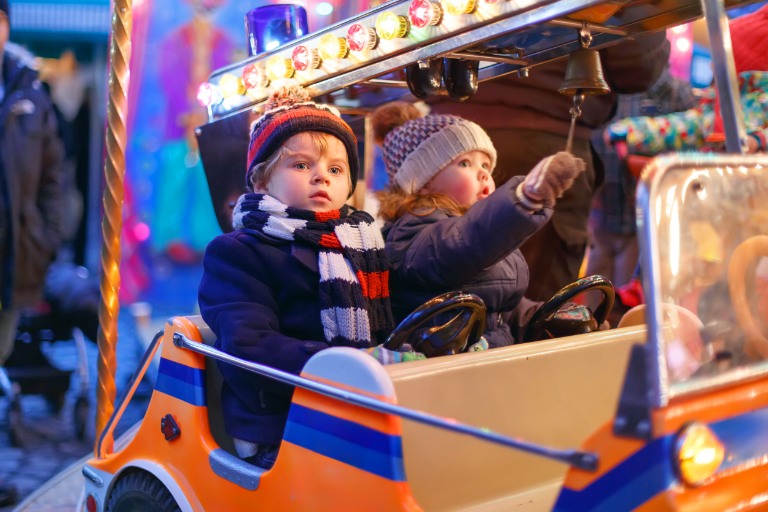 siblings on a carousel at Christmas funfair