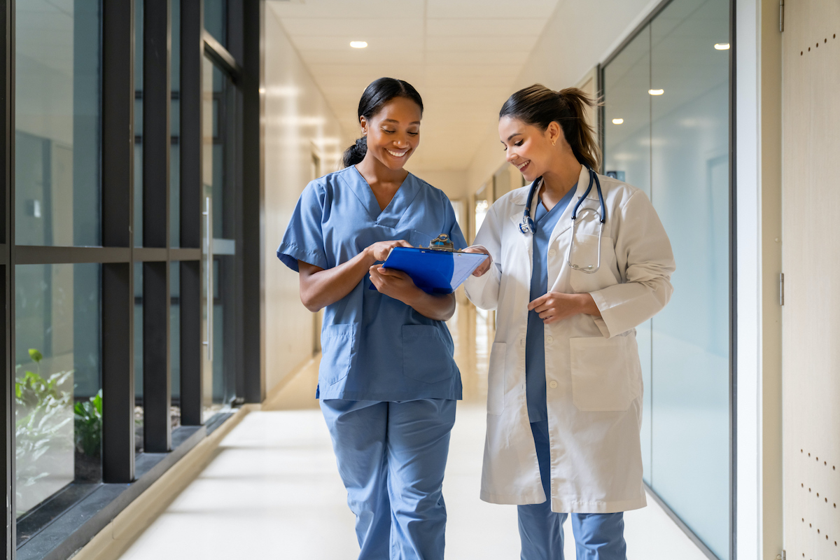 Happy nurse at the hospital showing tests results to a doctor and smiling – healthcare and medicine concepts
